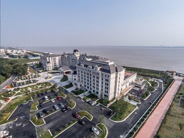 Un hotel grande con varias construcciones, un estacionamiento y vista al agua.