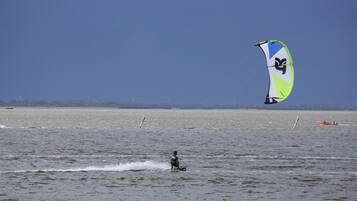 Une personne pratiquant la planche à voile sur une étendue d’eau sous un ciel dégagé.