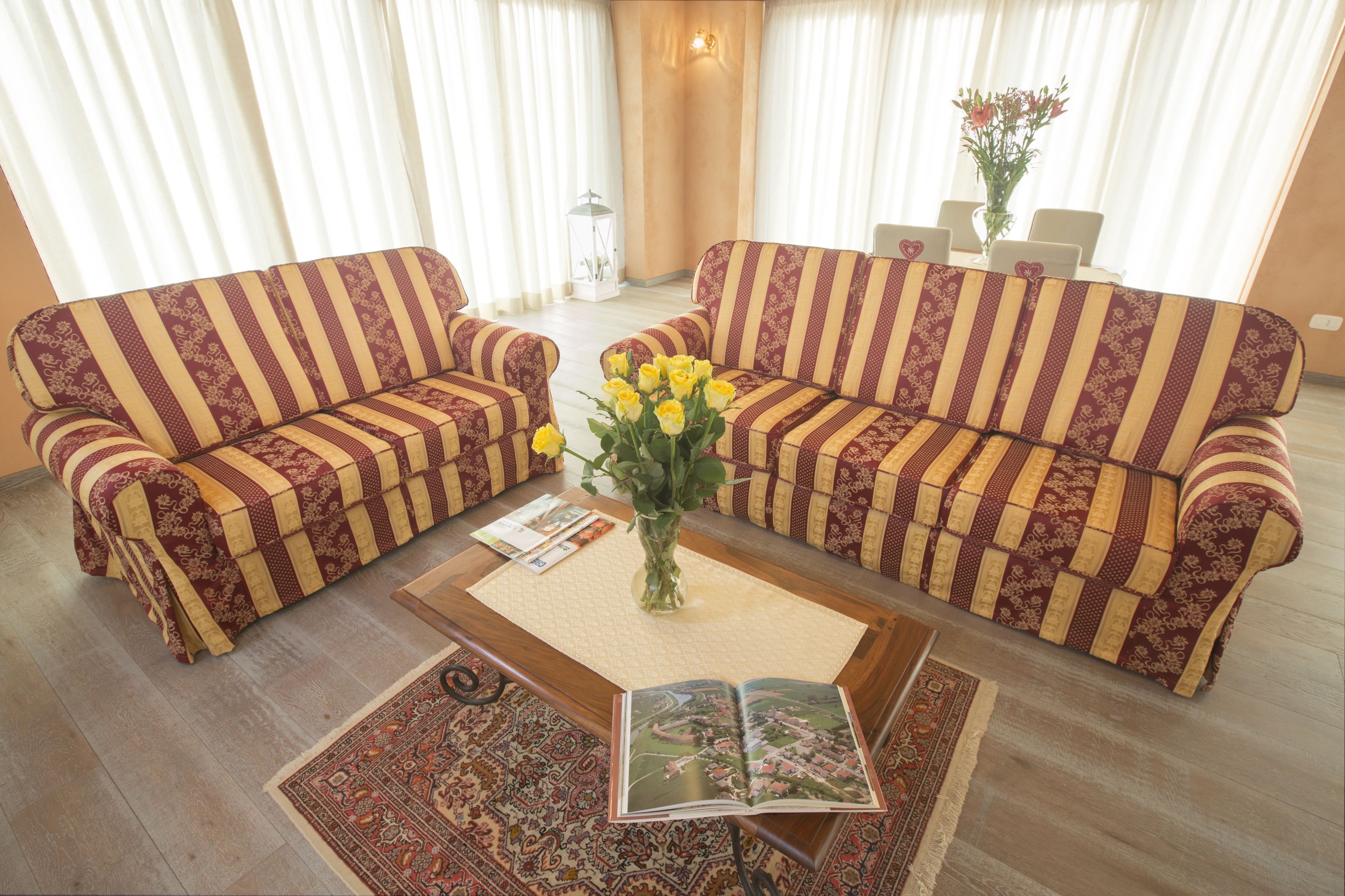 Un salon avec deux canapés à rayures, une table basse ornée d’un vase de fleurs jaunes et un tapis.