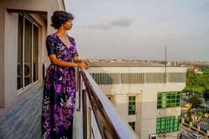 A woman standing on a balcony with a view of a cityscape.