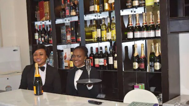 Una zona de bar con encimera de mármol, una botella de champán y una copa de vino.