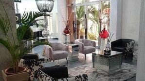 Amplia sala de estar con una lámpara moderna, asientos cómodos y un ventanal con vistas a palmeras.