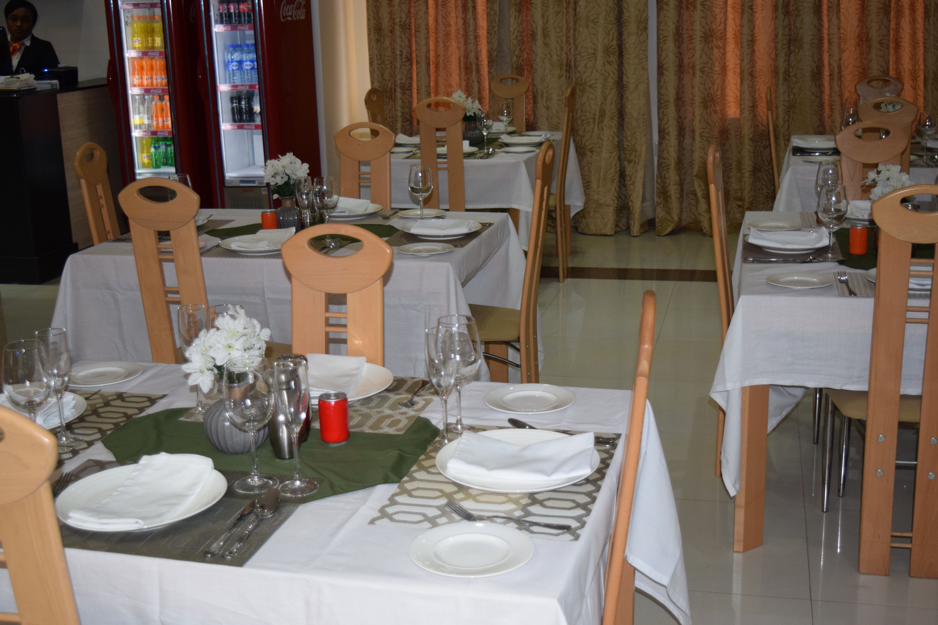 A restaurant with multiple tables set for dining, each with chairs, plates, cutlery, and glassware.