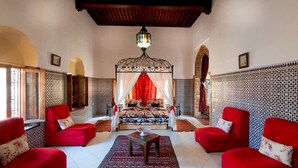 A room with a bed, red sofas, a patterned rug, and a decorative ceiling light. - Riad Dar Jabador (Salé)