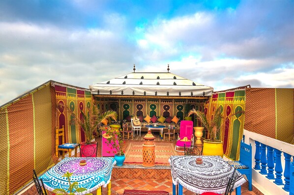 A courtyard with a central seating area, surrounded by patterned walls and potted plants.