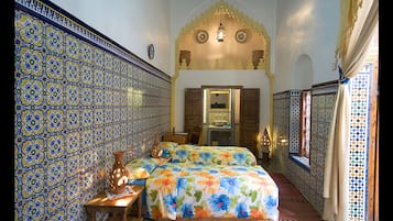 Traditional room with intricate tile work, wooden door, and floral-patterned bedding.
