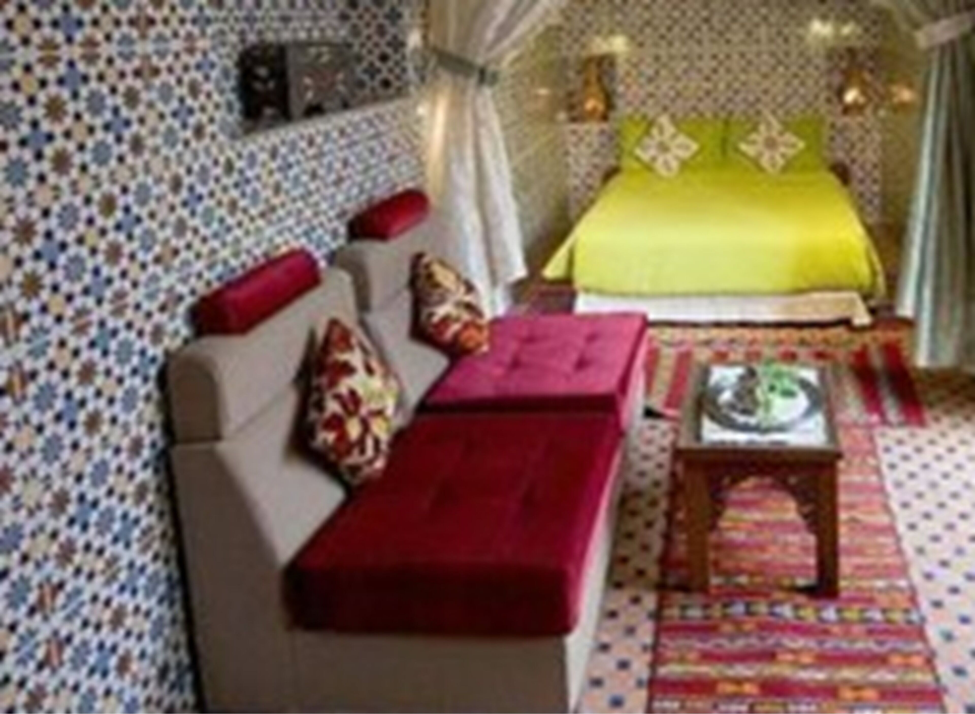 A room with a bed, a sofa, a small table, and a patterned wall.