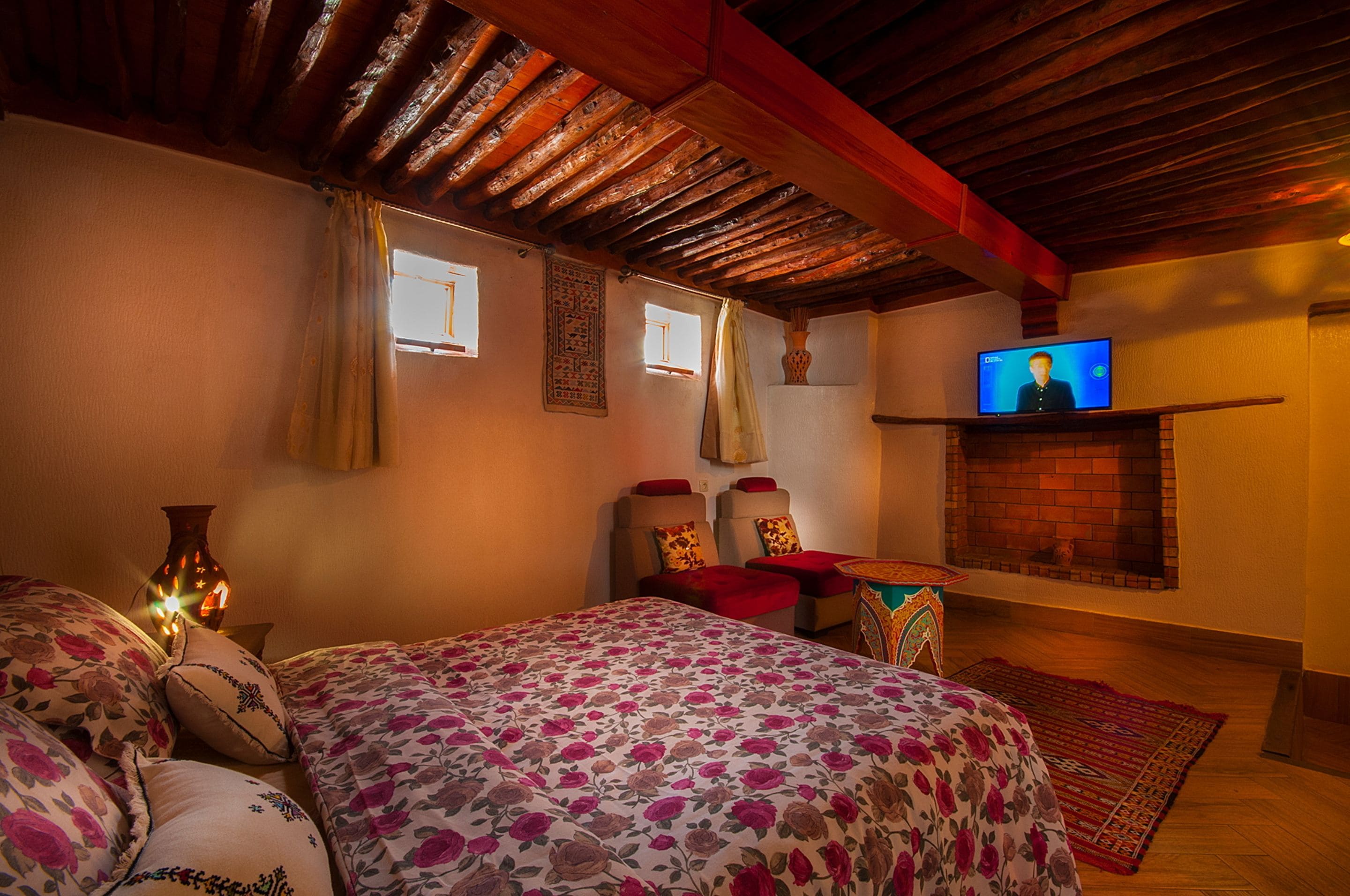 Ein gemütliches Zimmer mit Bett, Fernseher, Kamin und einem dekorativen Teppich.