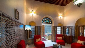 A traditional interior with red sofas, a TV, and patterned walls. - Riad Dar Jabador (Salé)