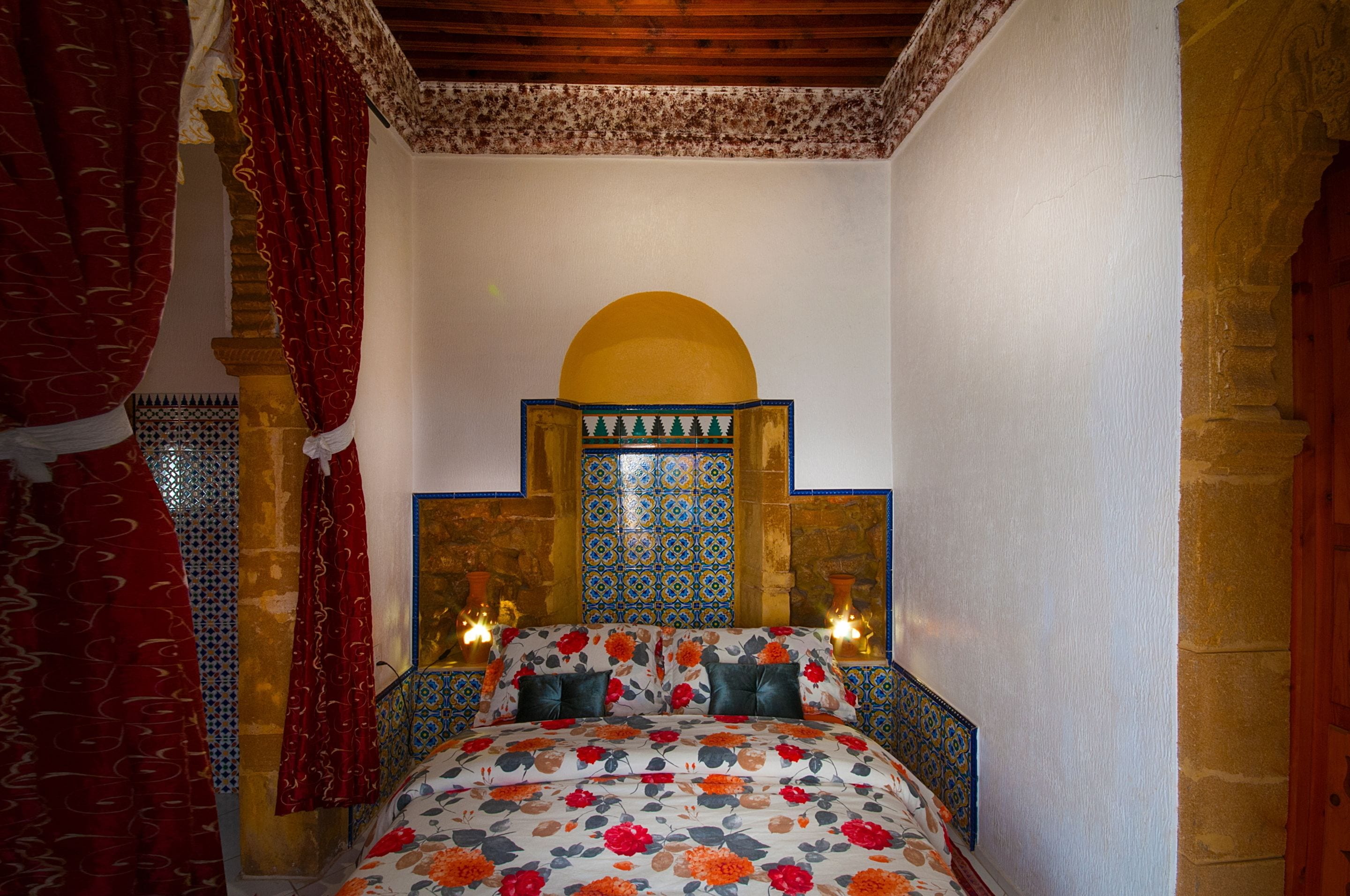 Una habitación con una cama, un cabecero decorativo y una pared con un diseño geométrico.