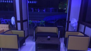 A seating area with sofas and a coffee table, a fan, and a view of a slide. - Copenhagen Hotel (Alanya)