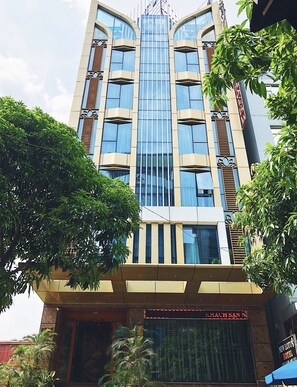A modern hotel with a glass facade, multiple balconies, and a prominent entrance with a sign. - New Lotus Hotel (Hanoi)