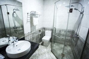 A modern bathroom with a glass-enclosed shower, a white sink, and a toilet. - New Lotus Hotel (Hanoi)