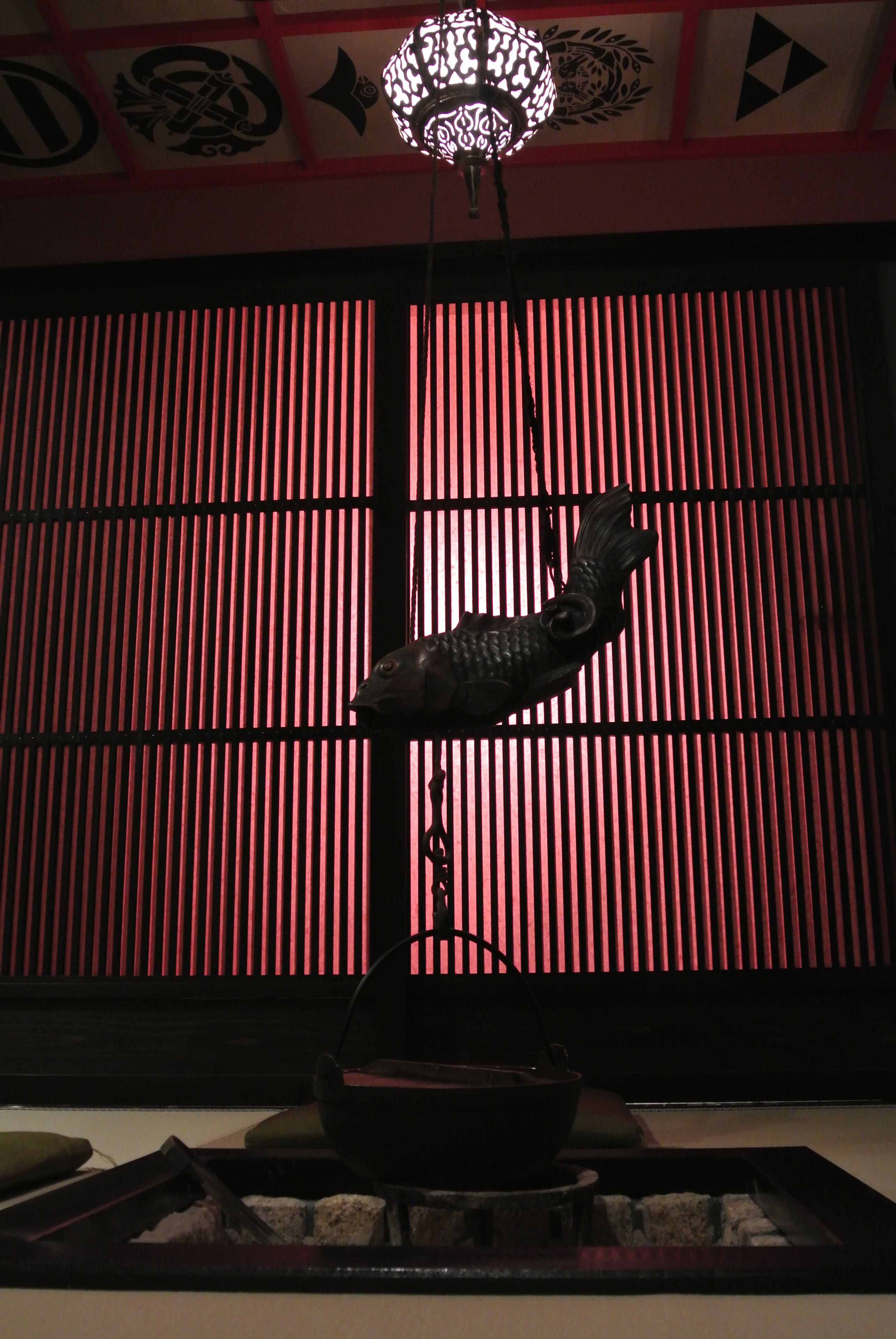 A traditional Japanese room with a shoji screen, a hanging fish sculpture, and a decorative light fixture.