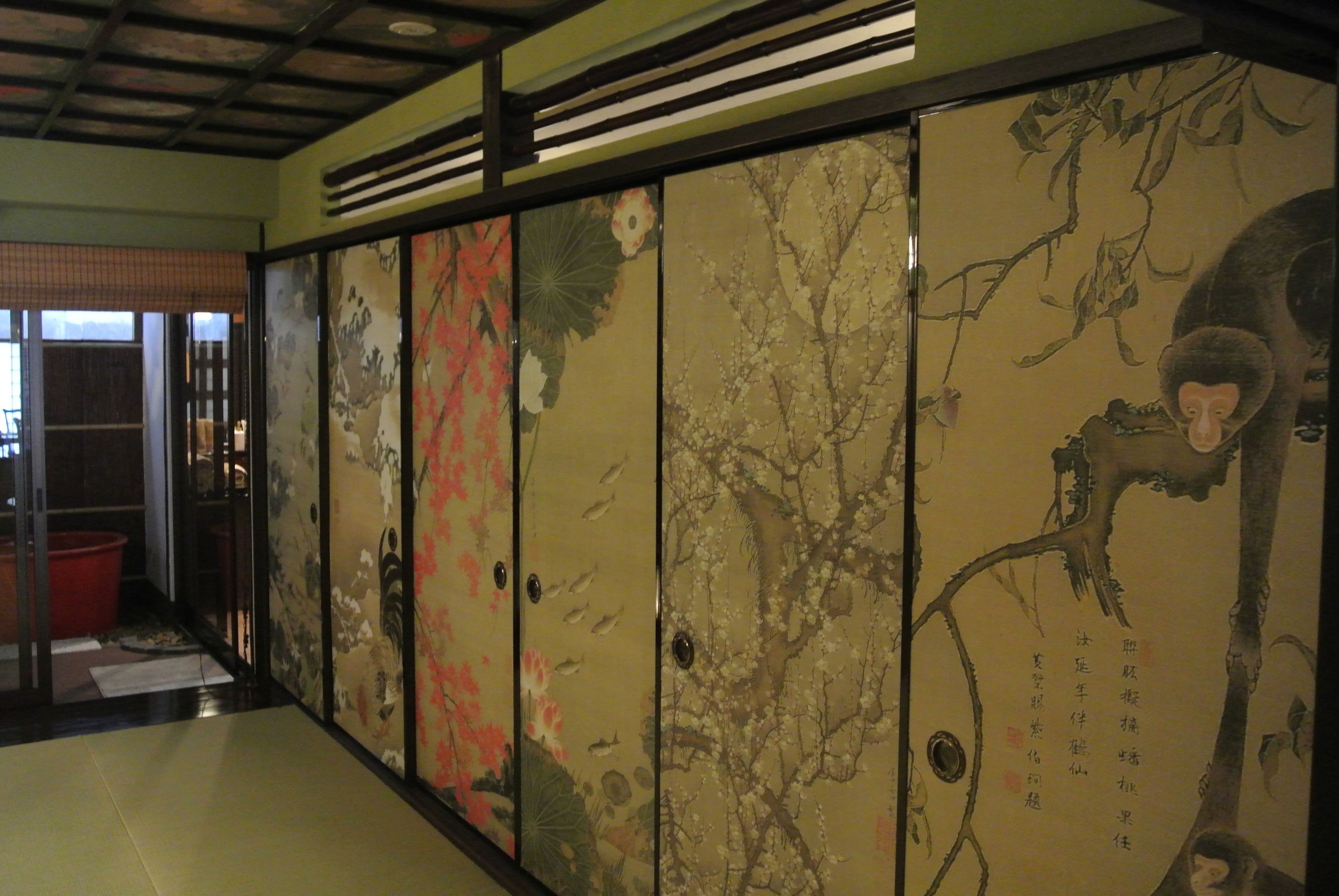 Une pièce de style japonais traditionnel, dotée de portes coulissantes ornées de motifs floraux et de représentations de la nature.