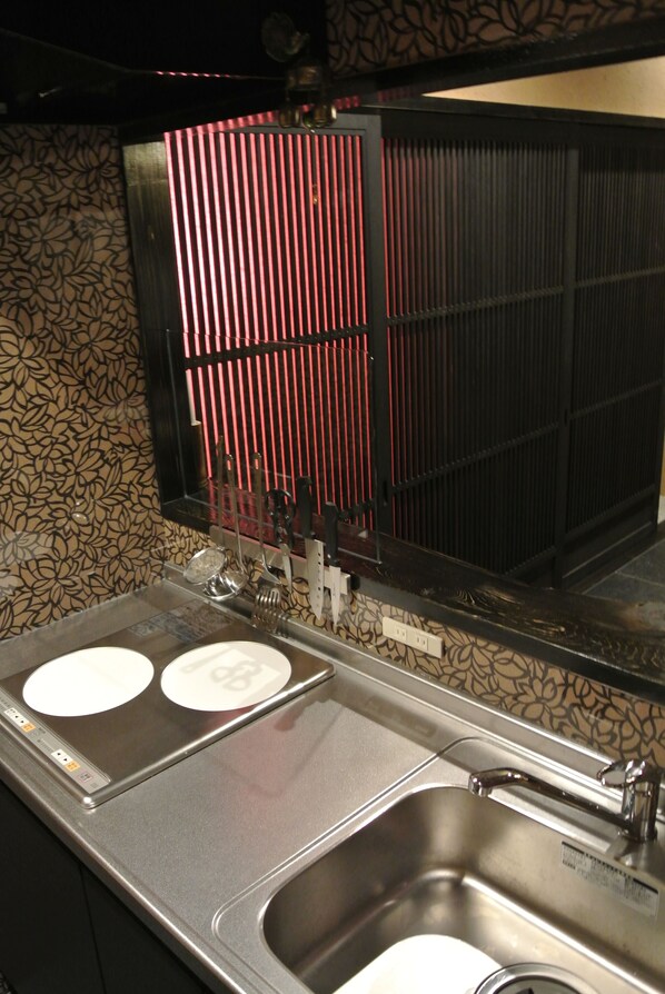 A kitchen with two stainless steel sinks, a black refrigerator, and a patterned backsplash.