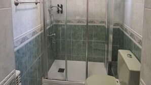 Une salle de bain avec une douche à parois de verre, des toilettes et un lavabo.