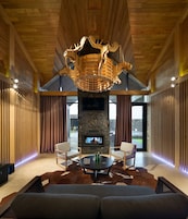 Um interior moderno com lareira de pedra, teto de madeira e uma grande janela.