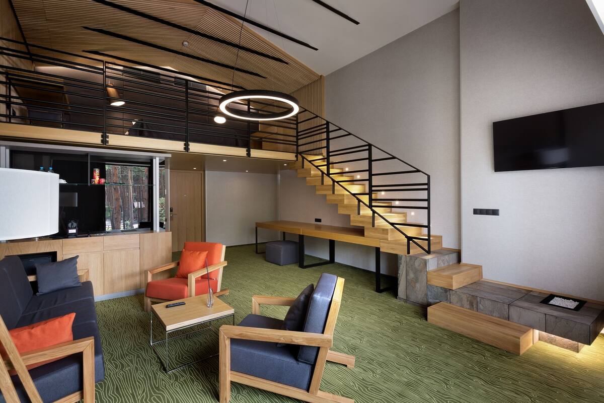 A modern interior with a staircase, seating area, and a flat-screen TV mounted on the wall.