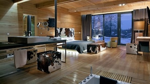 Un interno moderno in legno con un letto grande, un bagno con lavandino e specchio, e vista sull'esterno.