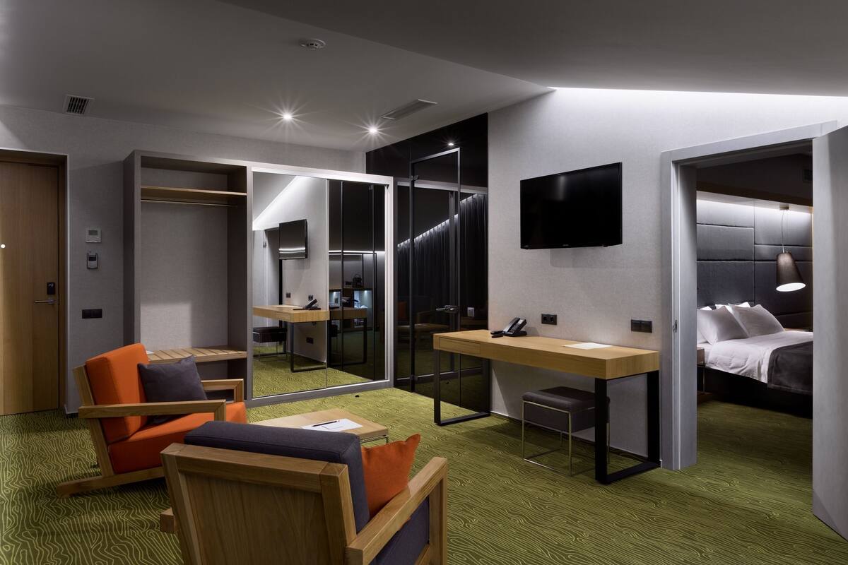 A modern hotel room with a desk, chair, and bed.