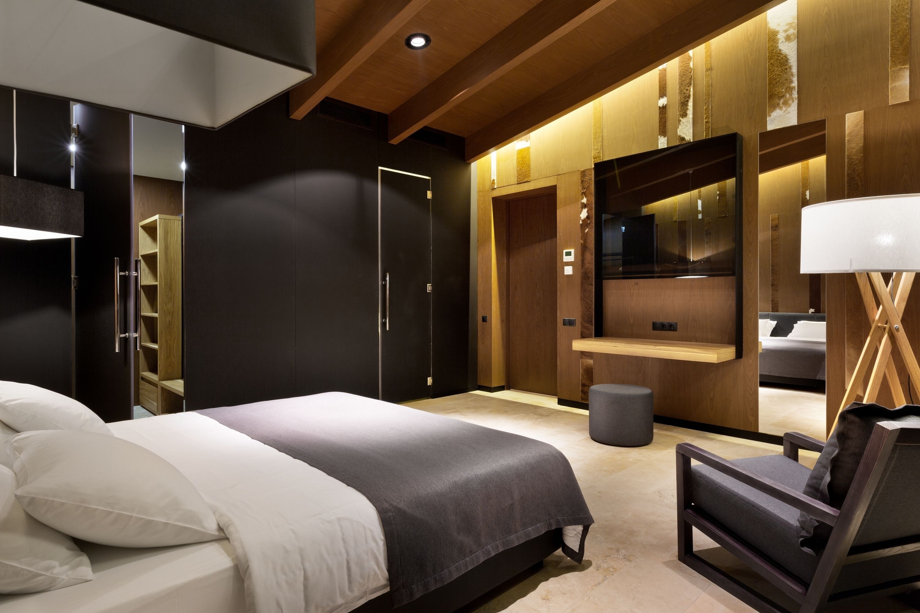 A modern bedroom with a bed, a chair, a vanity, and a mirror.