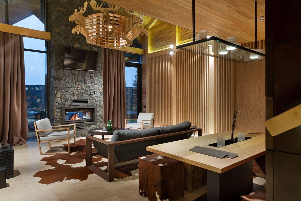 A modern living room with a fireplace, wooden furniture, and a large window.