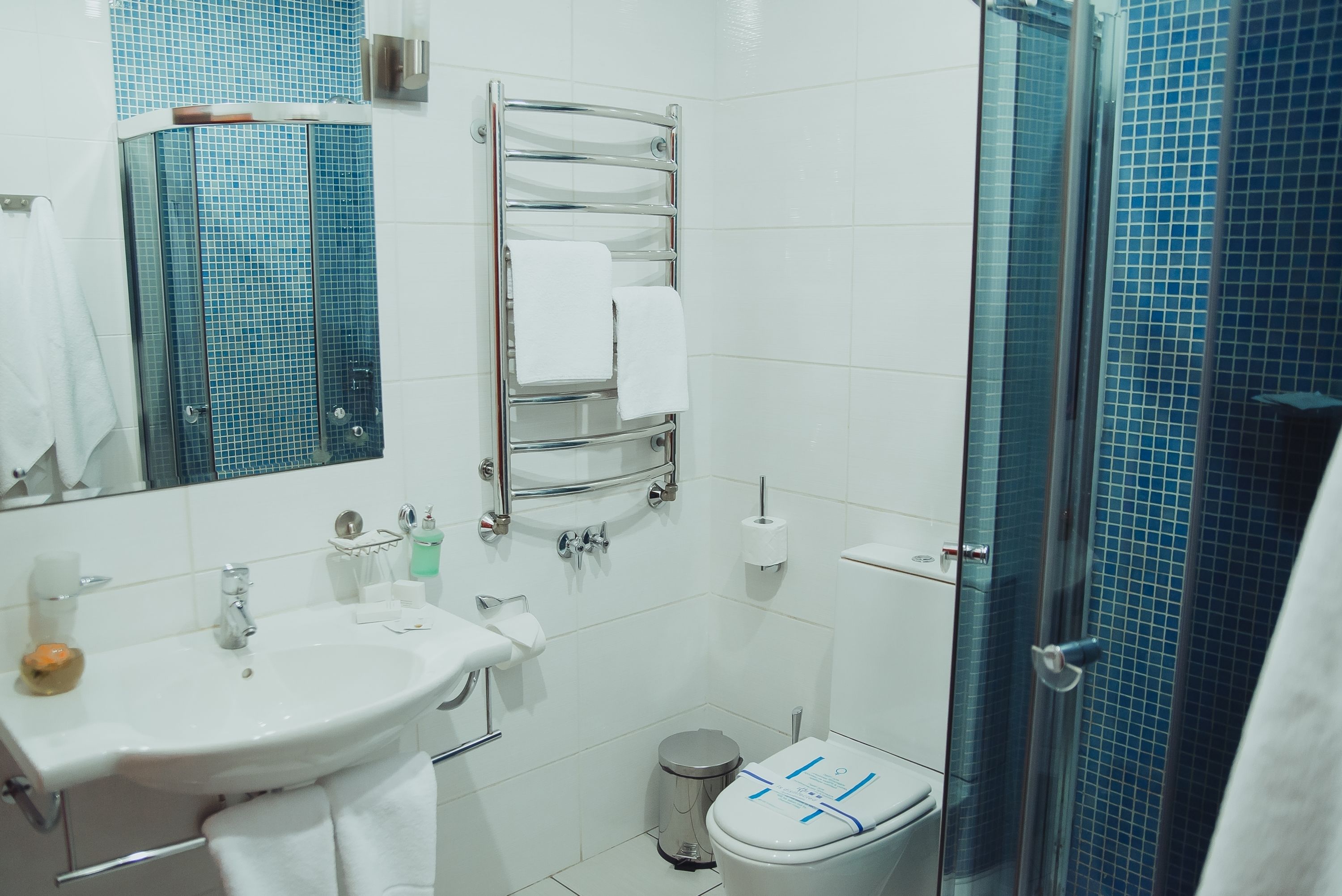 Un baño con lavamanos, espejo, toallero, inodoro y cabina de ducha de vidrio.