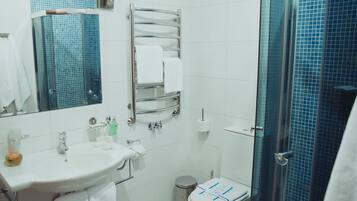 Un baño con lavamanos, espejo, toallero, inodoro y cabina de ducha de vidrio.