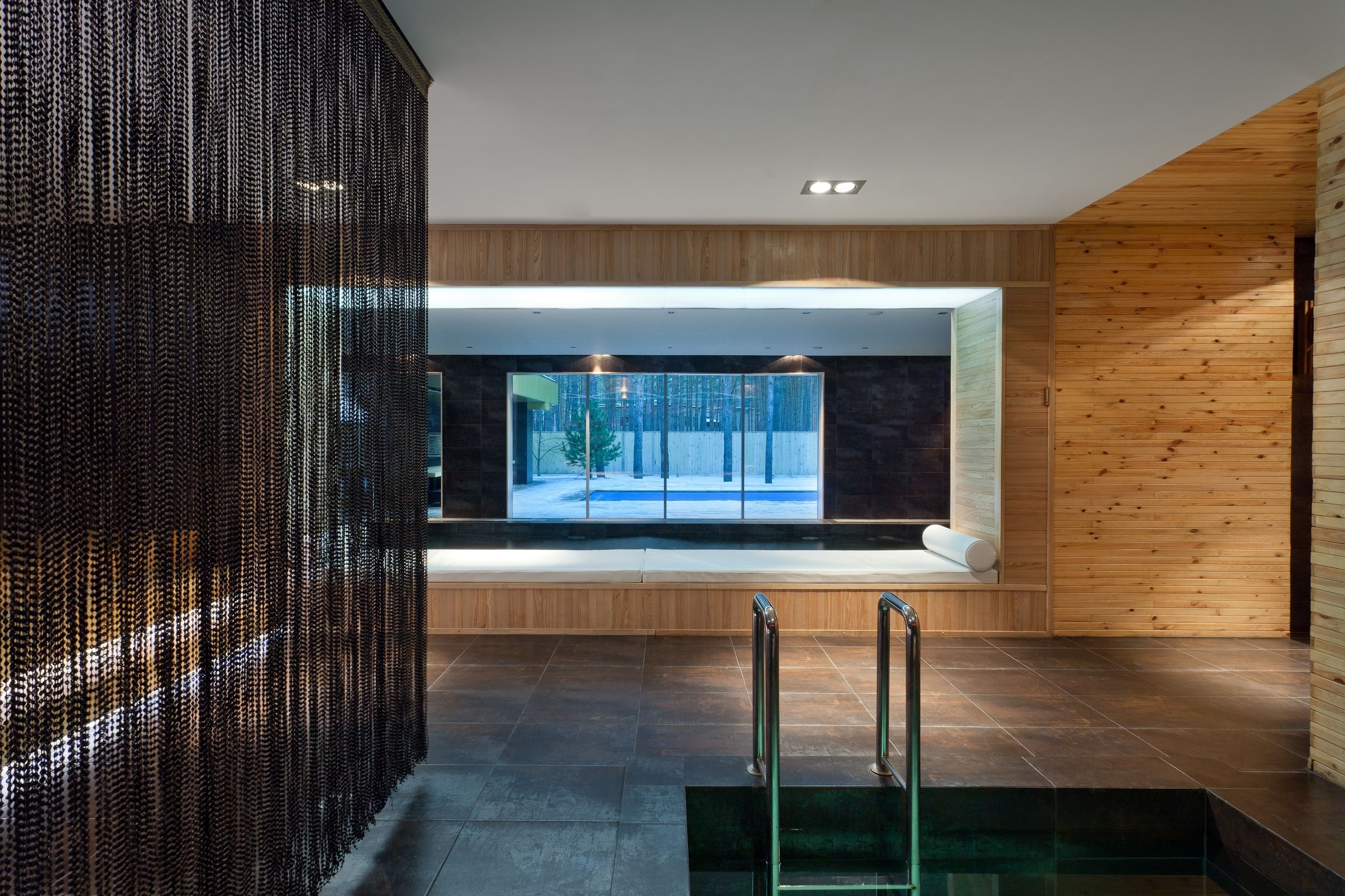 A modern interior with a large window, wooden panel walls, and a glass staircase.