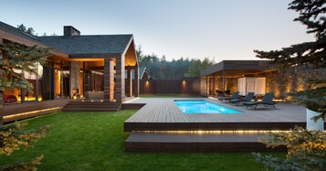 Uma casa moderna com piscina, deck de madeira e área de estar externa.