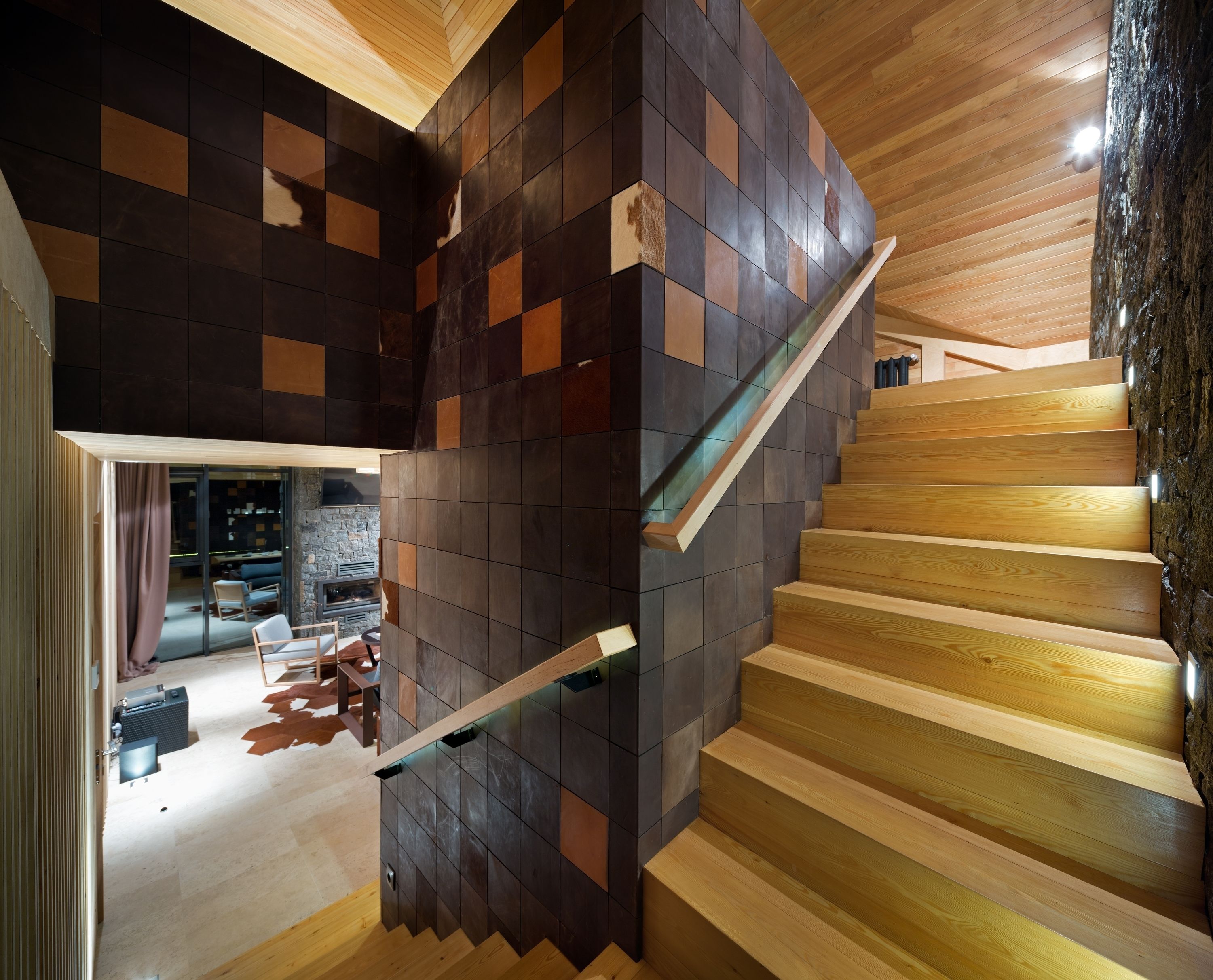 A modern staircase with wooden steps and a wall of dark tiles.