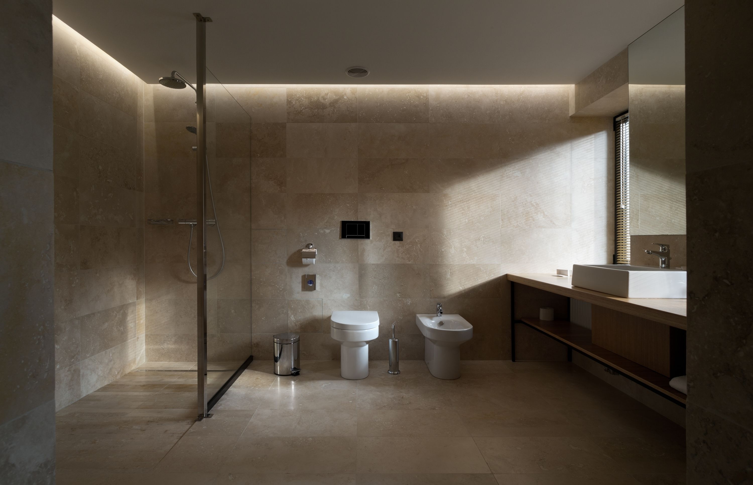 Un baño moderno con ducha a ras de suelo, inodoro, bidé y lavamanos.