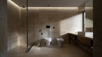 Un baño moderno con ducha a ras de suelo, inodoro, bidé y lavamanos.