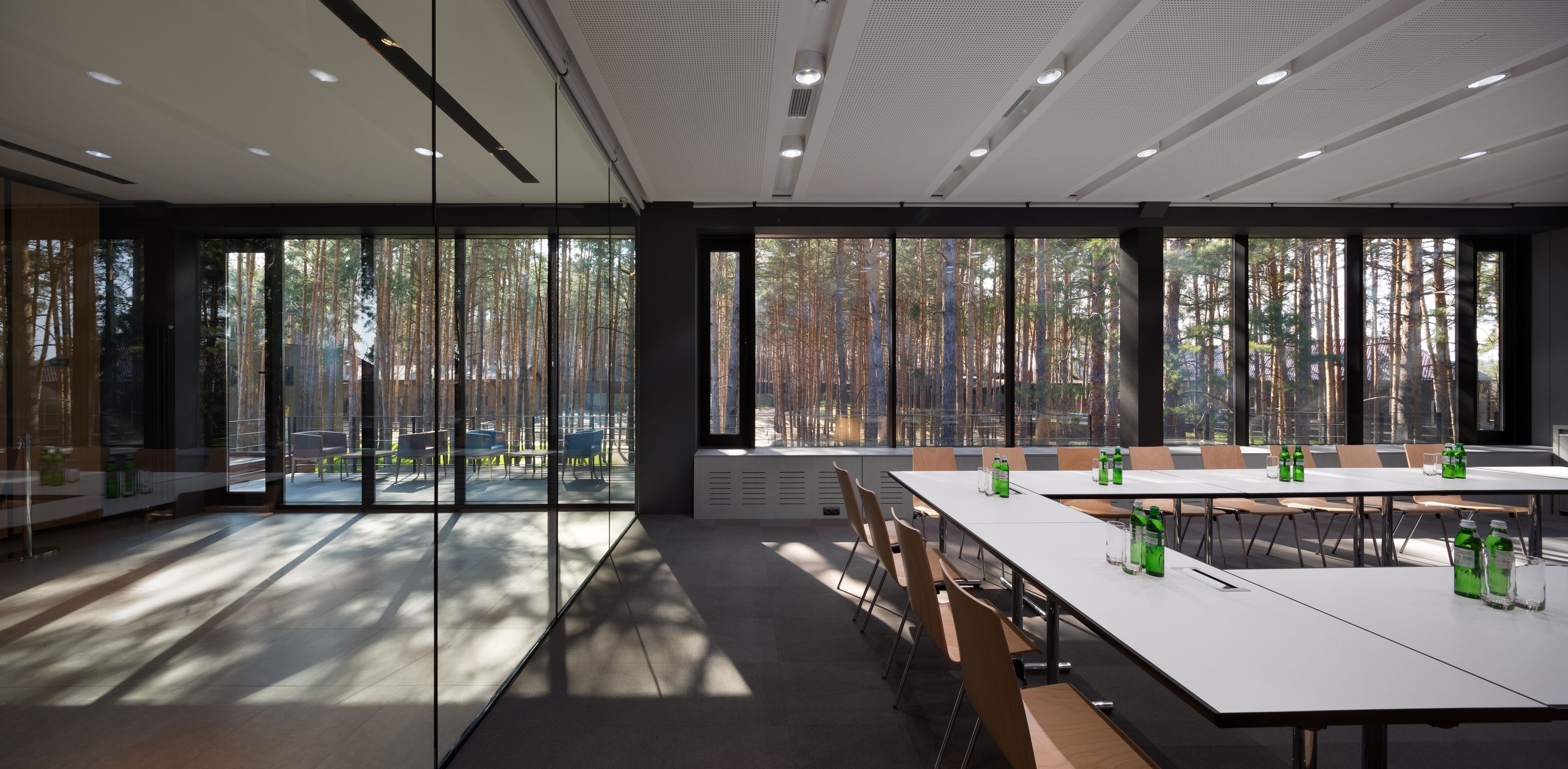 A conference room with large windows, white tables, and chairs.