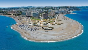 An aerial view of a coastal area with a beach, a large hotel complex, and surrounding buildings. - Stavros Pension (Rhodes)
