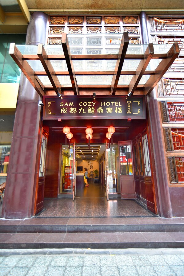 L’entrée de l’hôtel Sam Cozy présente des éléments d’architecture chinoise traditionnelle et une enseigne en anglais et en chinois.