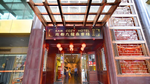 La entrada al Hotel Sam Cozy, con elementos arquitectónicos chinos tradicionales y un letrero en inglés y chino.