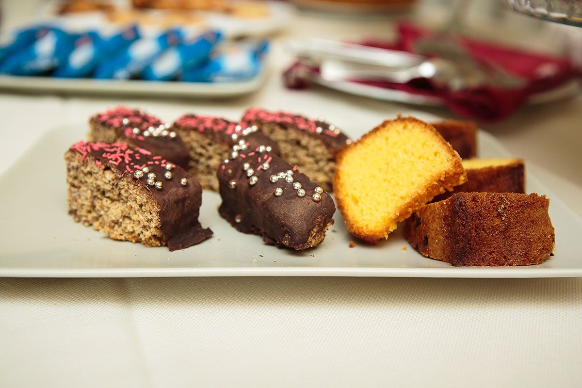 Une assiette contenant différents types de gâteaux, notamment des morceaux enrobés de chocolat et décorés de vermicelles, ainsi qu’une part de gâteau jaune.