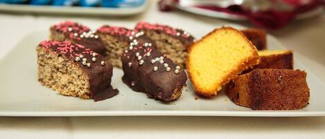 Une assiette contenant différents types de gâteaux, notamment des morceaux enrobés de chocolat et décorés de vermicelles, ainsi qu’une part de gâteau jaune.