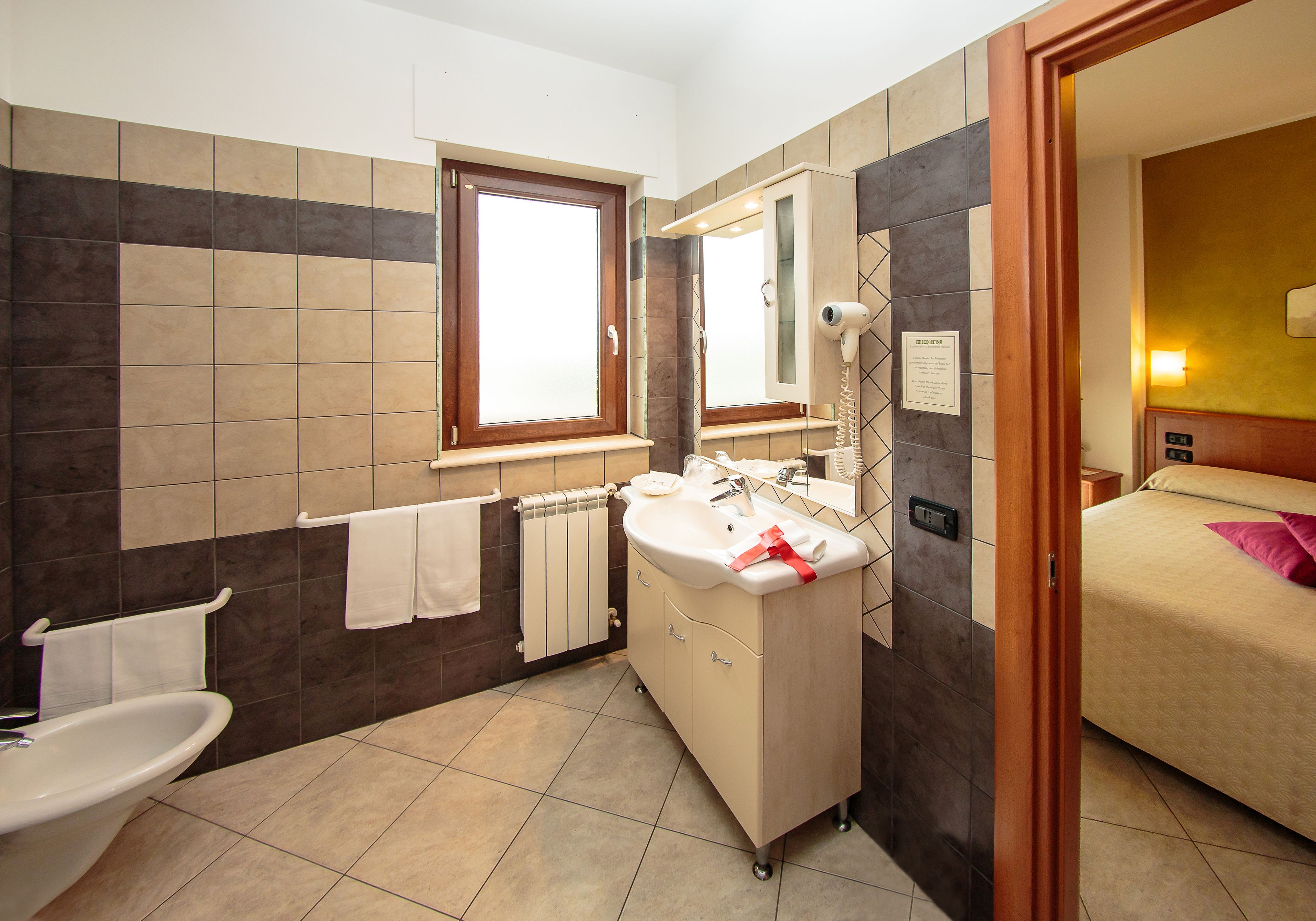 Un baño moderno con lavamanos, espejo y toallero.