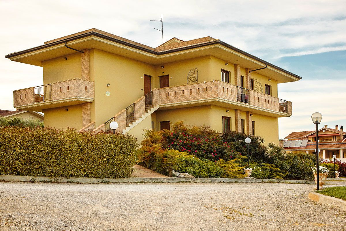A two-story house with a balcony, a staircase, and a garden.