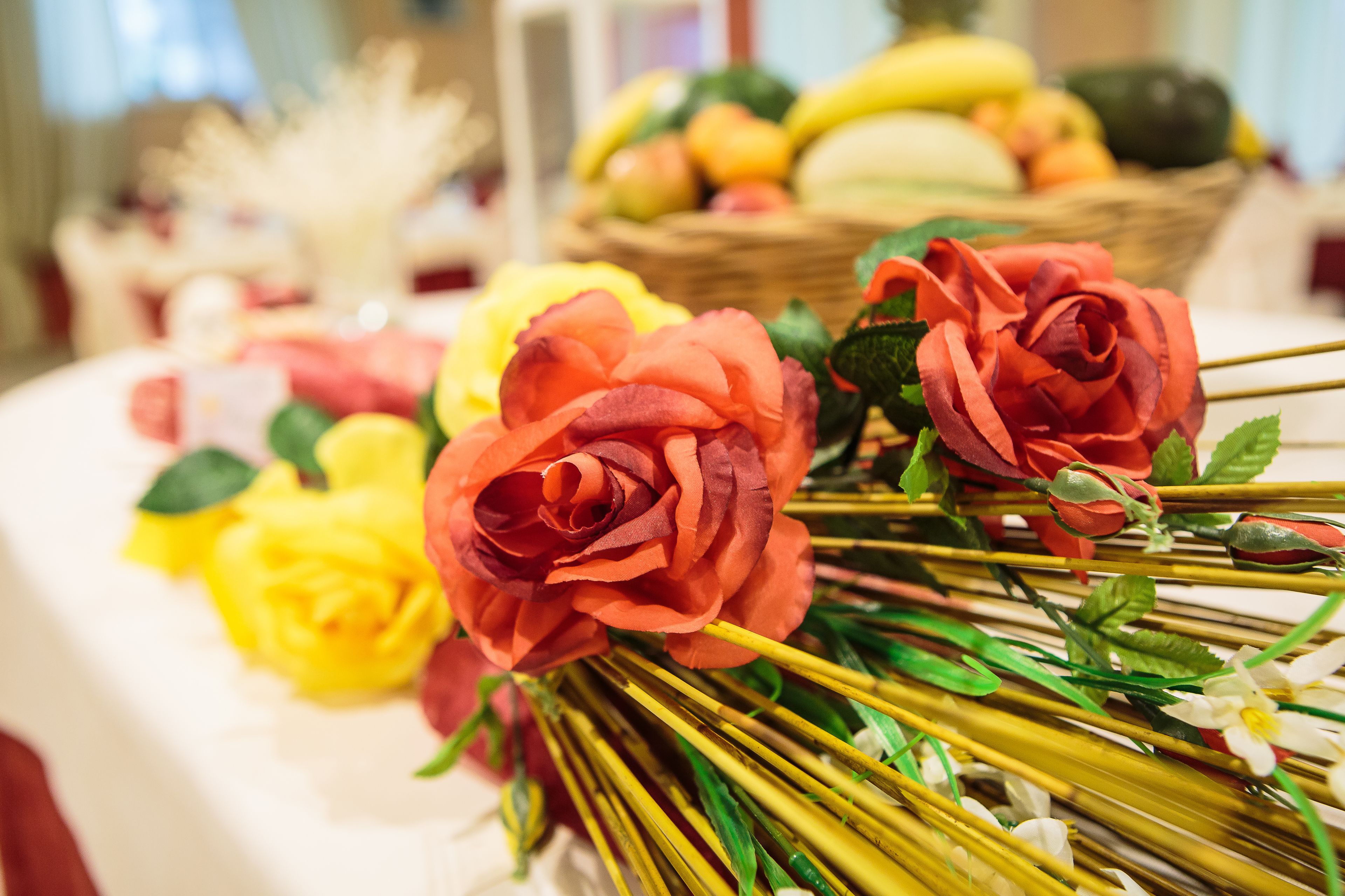 Ein Tisch mit künstlichen Blumen und einer Obstkorb.