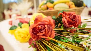 Ein Tisch mit künstlichen Blumen und einer Obstkorb.