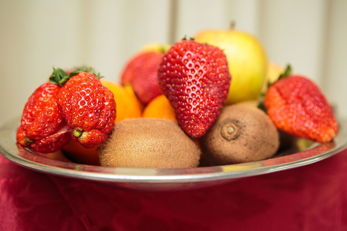 A bowl containing strawberries, kiwis, and an apple.