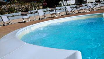 A swimming pool with lounge chairs and umbrellas.