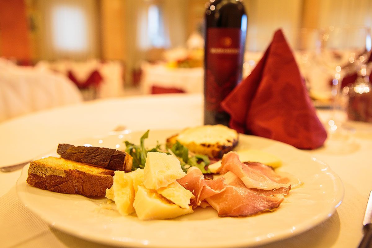 Un piatto con pane tostato, patate e prosciutto su un tavolo in sala da pranzo.