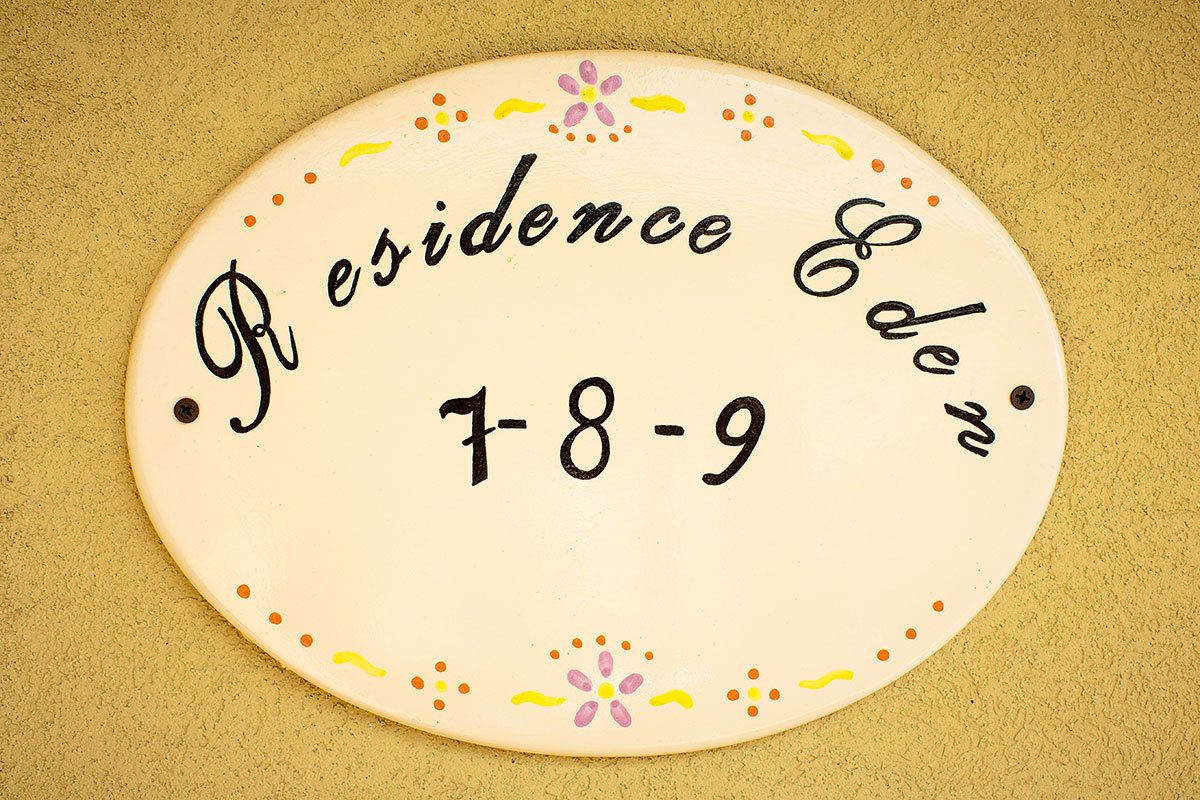 A circular plaque with the text "Residence Eden 7-8-9" surrounded by decorative dots and flowers.