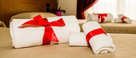 Neatly folded towels with red ribbons on a bed in a hotel room.