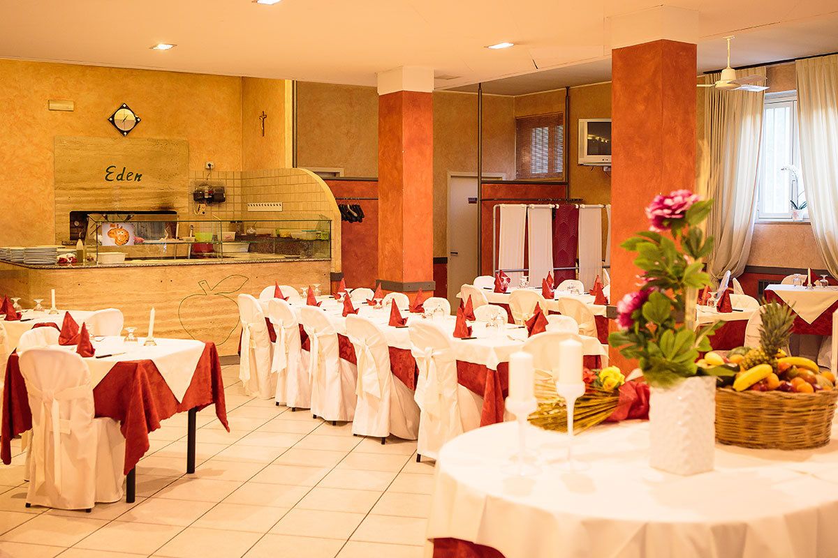 A dining area with round tables, white tablecloths, and red napkins.